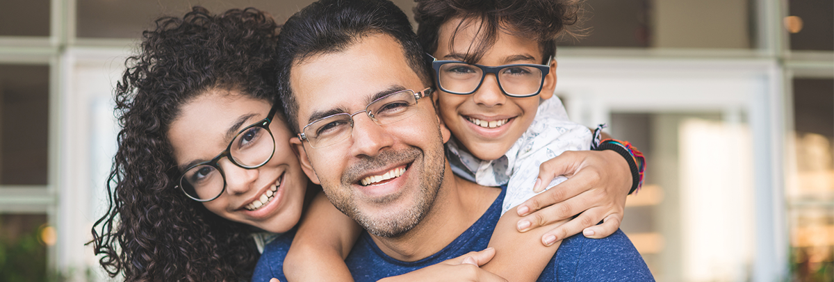 Smiling family wearing glasses while hugging their father