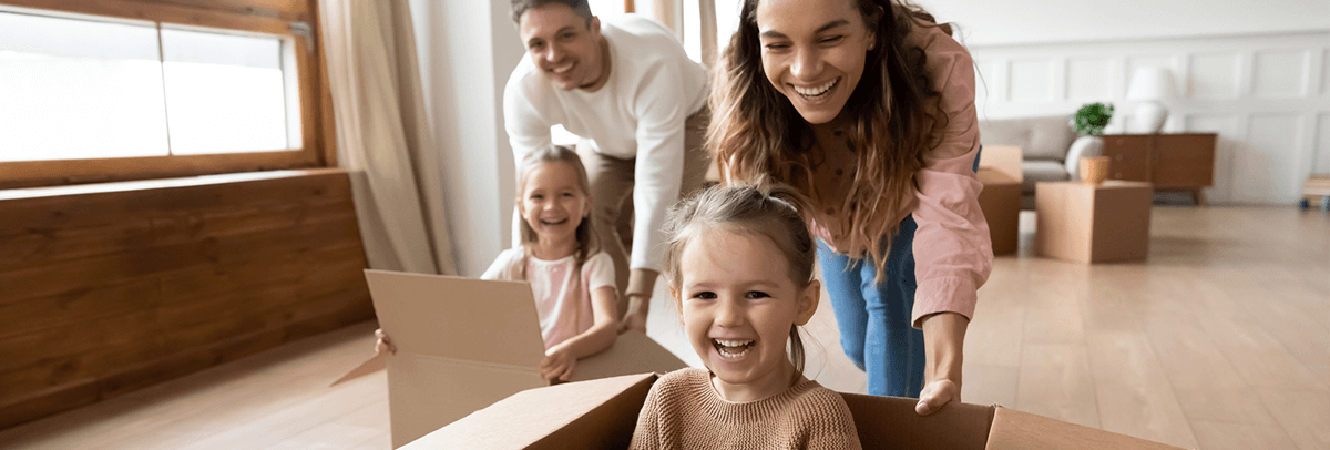 Mortgage-Homeownership Parents giving their children rides along floor in cardboard boxes